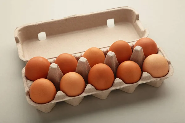 Chicken eggs in an open egg carton on grey. Natural healthy food and organic farming concept.