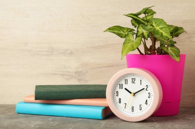 Front view desk with clock, books and plant on light background. Copy space. Top view