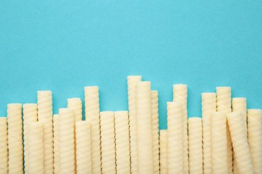 Delicious milk wafer rolls on blue background. Top view