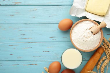 Ingredients for baking or cooking, egg flour, rolling pin butter, milk on blue background Cookie pie or cake recipe. Top view.