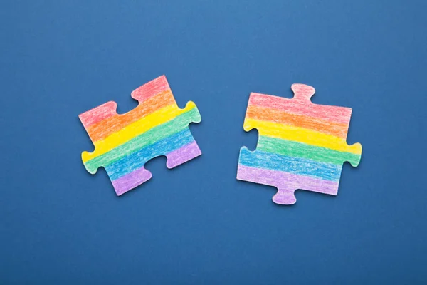 Concept LGBT as a part of society - two puzzle with the coloring of the flag of sexual minorities on dark blue background. Top view