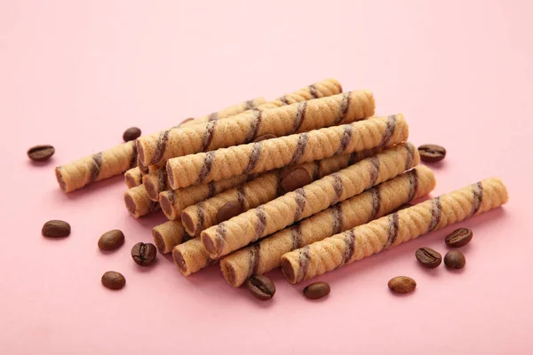 Coffee wafer stick roll with coffee cream on pink background. Top view