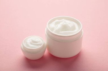 Jar with cream on pink background, space for text. Top view