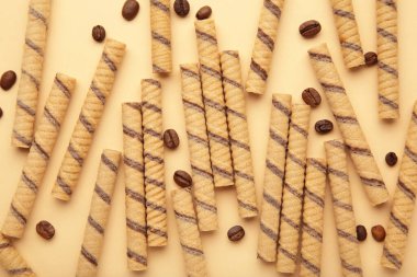 Coffee wafer stick roll with coffee cream on beige background. Top view