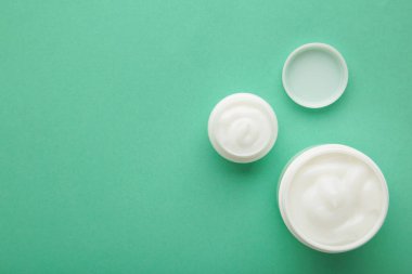 Jar with cream on mint background, space for text. Top view