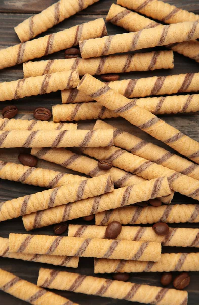 Close-up of striped wafer rolls on dark background. Background or texture