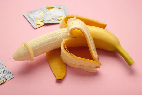 Condom and banana on pink background with copy space. Top view