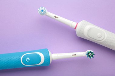 Mor arka planda iki modern elektrikli diş fırçası. Üst Manzara. Diş bakımı. Minimalizm