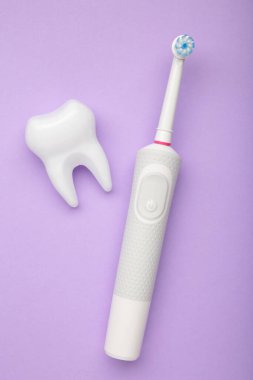 Mor arka planda modern elektrikli diş fırçası. Günlük oral bakım için kontrol edilen bir araç. Mesaj için yer var. Dikey fotoğraf