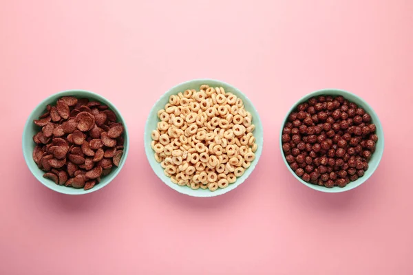Set of various breakfast cereals on pink background, top view
