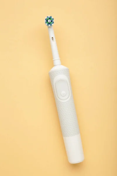 ベージュ地にモダンな電動歯ブラシ 毎日の口腔ケアのための制御ツール 垂直写真 — ストック写真