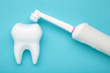 Mavi arka planda modern elektrikli diş fırçası. Günlük oral bakım için kontrol edilen bir araç. Metin için boşluk
