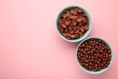 Pembe arka planda çeşitli kahvaltı gevrekleri, üst manzara.