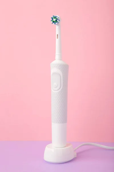 ピンクの背景に充電器と現代の電動歯ブラシ トップ表示 — ストック写真