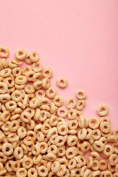 Whole grain cereal rings on pink background. Vertical photo. Top view