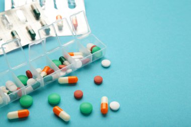 Mavi arka planda ilaç ve besin takviyeleri olan günlük ilaç kutusu. Üst görünüm