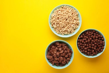 Sarı arka planda çeşitli kahvaltı gevrekleri, üst manzara. Metin için boşluk