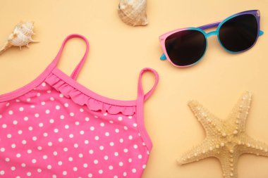 Yaz çocuğunun tatil konsepti. Bej arka planda şirin güneş gözlüklü mayo. Tatil konsepti, moda çocuğu. Üst görünüm