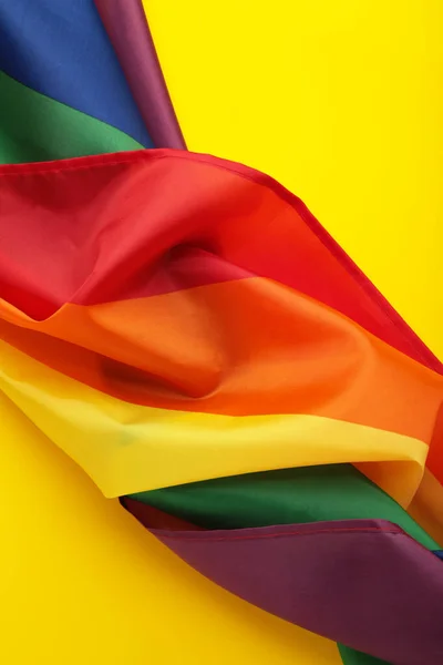 The rainbow flag (LGBT) on yellow background. Vertical photo. Top view