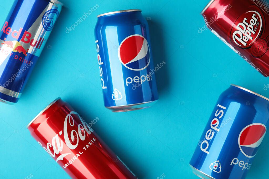 Mykolaiv, Ukraine - May 2, 2023: Cans of Coca cola, Pepsi, Dr.Pepper and Red Bull on blue background. American multinational beverage company. Top view