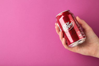 Mykolaiv, Ukrayna - 2 Mayıs 2023: Pembe arka planda Dr Pepper 'ın el ele tutuştuğu alüminyum kutu. Üst görünüm