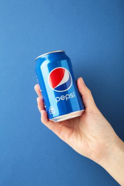 Mykolaiv, Ukrayna - 2 Mayıs 2023: Mavi arka planda Pepsi kutusunu tutan kadın. Üst görünüm