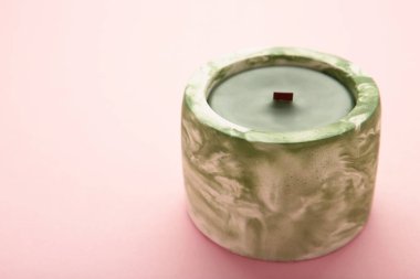 Pembe arka planda beton bir şamdanda mum. Üst görünüm