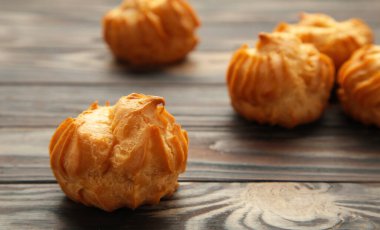 Kahverengi arka planda kremalı ev yapımı profiterol. Taze pişmiş altın profiterol. Üst görünüm.