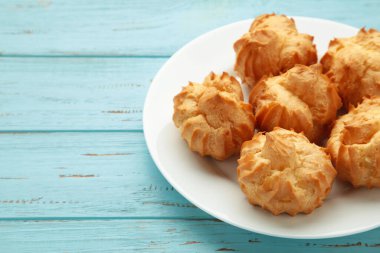 Mavi arka planda kremalı ev yapımı profiteroller. Taze pişmiş altın profiterol. Üst görünüm.