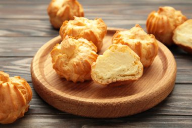 Kahverengi arka planda kremalı ev yapımı profiteroller. Taze pişmiş altın profiterol. Üst görünüm.