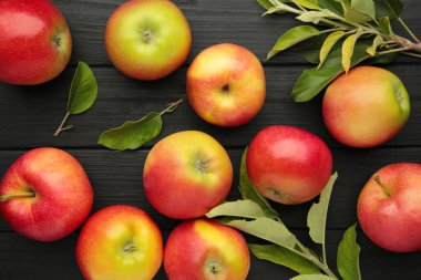 Siyah arka planda yaprakları olan bir grup kırmızı elma. Üst görünüm