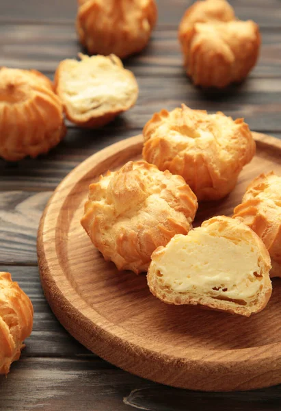 Kahverengi arka planda kremalı ev yapımı profiteroller. Taze pişmiş altın profiterol. Üst görünüm.