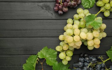 Siyah ahşap arka planda çeşitli üzümler. Mesaj için yer var. Üst görünüm