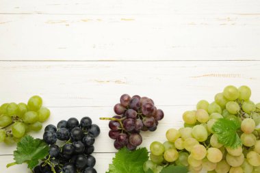 Beyaz ahşap arka planda çeşitli üzümler. Mesaj için yer var. Üst görünüm