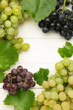 Beyaz ahşap arka planda çeşitli üzümler. Dikey fotoğraf. Çerçeve, mesaj için yer. Üst görünüm