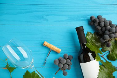 Mavi ahşap arka planda üzümlü şarap şişesi ve şarap kadehi. Mesaj için yer var. Üst görünüm