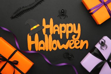 Hediye kutularıyla Mutlu Cadılar Bayramı yazıları, menekşe arkaplanlı örümcekler. Üst görünüm