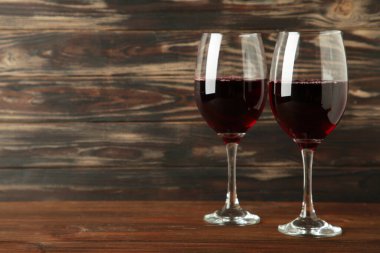 Koyu kahverengi arka planda kırmızı şarap kadehleri. Mesaj için yer var. Üst görünüm