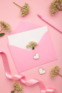 Zarflı kompozisyon ve pembe arka planda güzel çiçekler. Üst görünüm