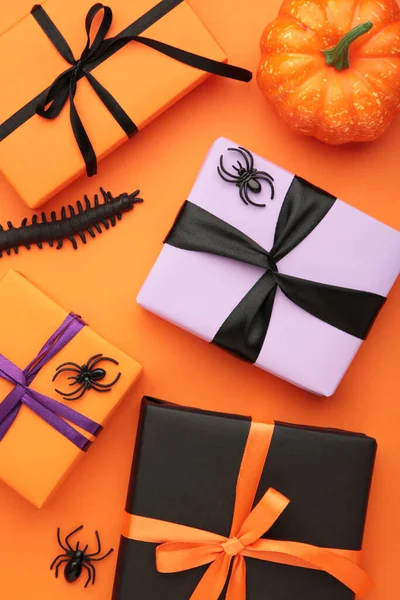 Happy Halloween holiday concept. Flat lay gift boxes, orange pumpkins, bats, spiders on orange background. Halloween greeting card template. Top view