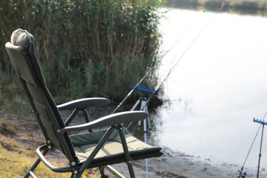 Gün doğumunda, sisli bir sabahta, arka planda balıkçı sandalyesi ve olta kamışı var. Balık tutma konsepti. Güzel gün doğumu - sabah manzarası. Sisin içinde elinde olta olan bir balıkçının mekanı. Üst görünüm