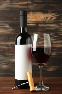 Kahverengi ahşap arka planda üzümlü şarap şişesi ve şarap kadehi. Dikey fotoğraf. Üst görünüm