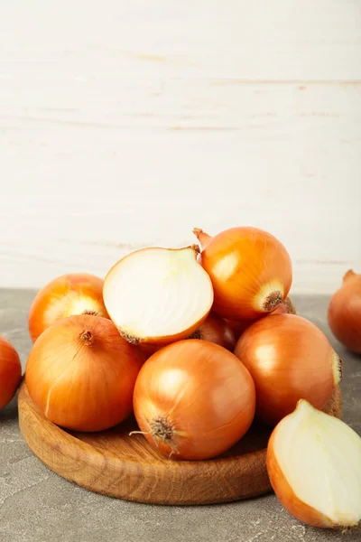 Fresh healthy onions and sliced onion on wooden board on white background. Vertical photo. Top view