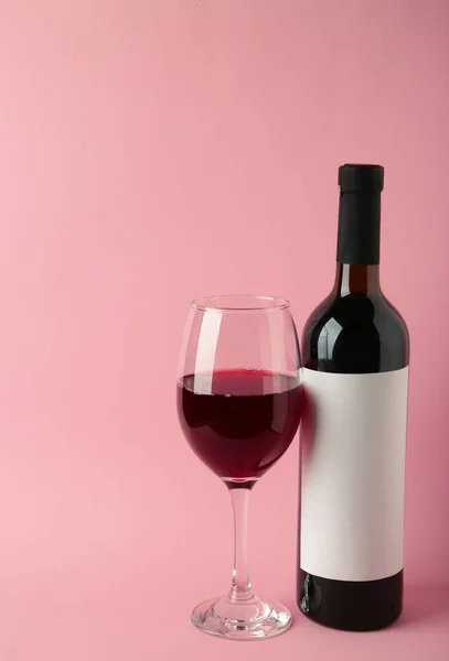 Wine bottle and wine glass on pink background. Vertical photo. Top view