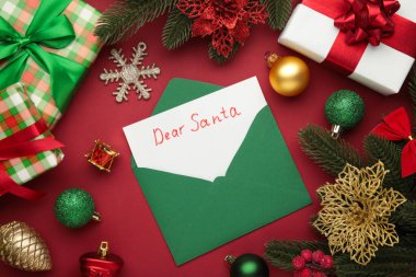 Sevgili Noel Baba, kırmızı arka planda Noel oyuncakları olan Noel Baba 'ya mektup. Üst görünüm