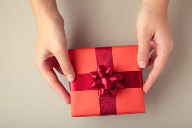 Kırmızı hediye ve gri arka planda kırmızı fiyonk. Mesaj için yer var. Üst görünüm