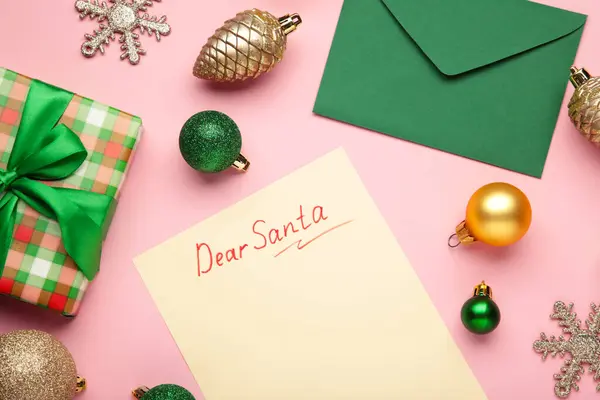 Christmas letter to Santa Claus with the words: Dear Santa. Christmas composition with yellow and green balls on pink background. Top view