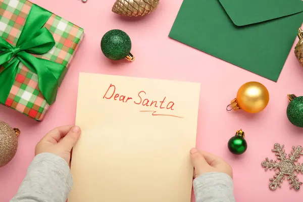 Christmas letter from a child to Santa Claus with the words: Dear Santa. Christmas composition with yellow and green balls. Top view