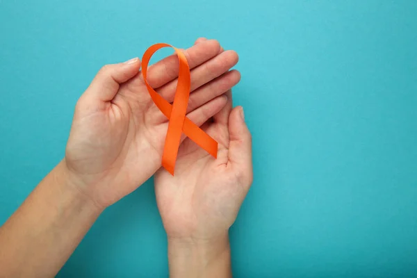 Handen Met Oranje Lint Blauwe Achtergrond Nierkankerbewustzijn Leukemie Bewustwording Van — Stockfoto