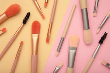 Makyaj için profesyonel kadın kozmetik fırçası ve pastel arka planda kirpik fırçası. Kozmetik konsepti, makyaj konsepti. Üst görünüm